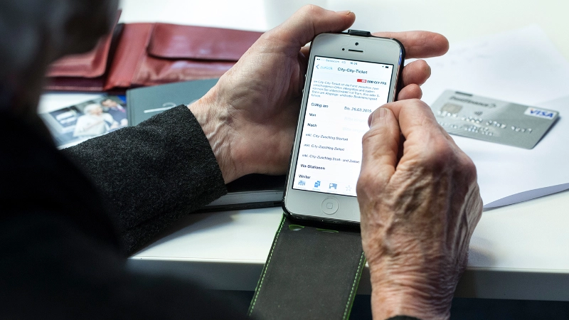 Ein Senior hält sein Ipad in den Händen und liest.
