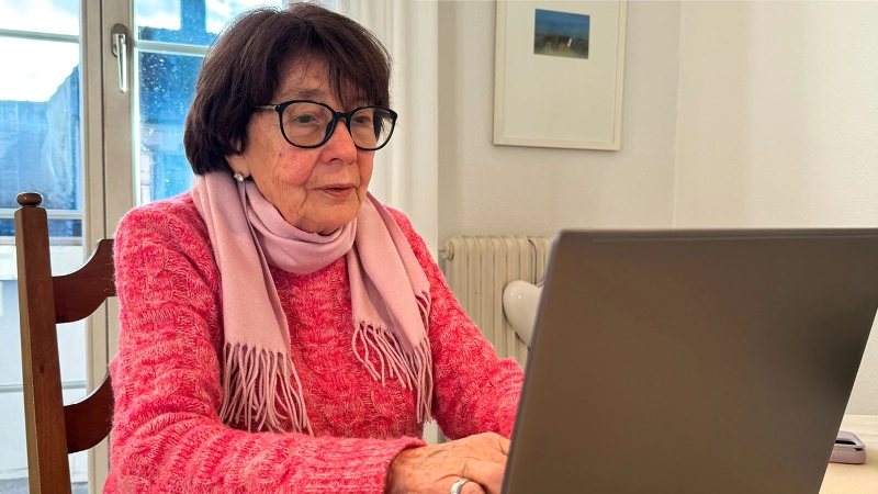 Liliane Gasser sitzt am Tisch mit ihrem neuen Laptop.