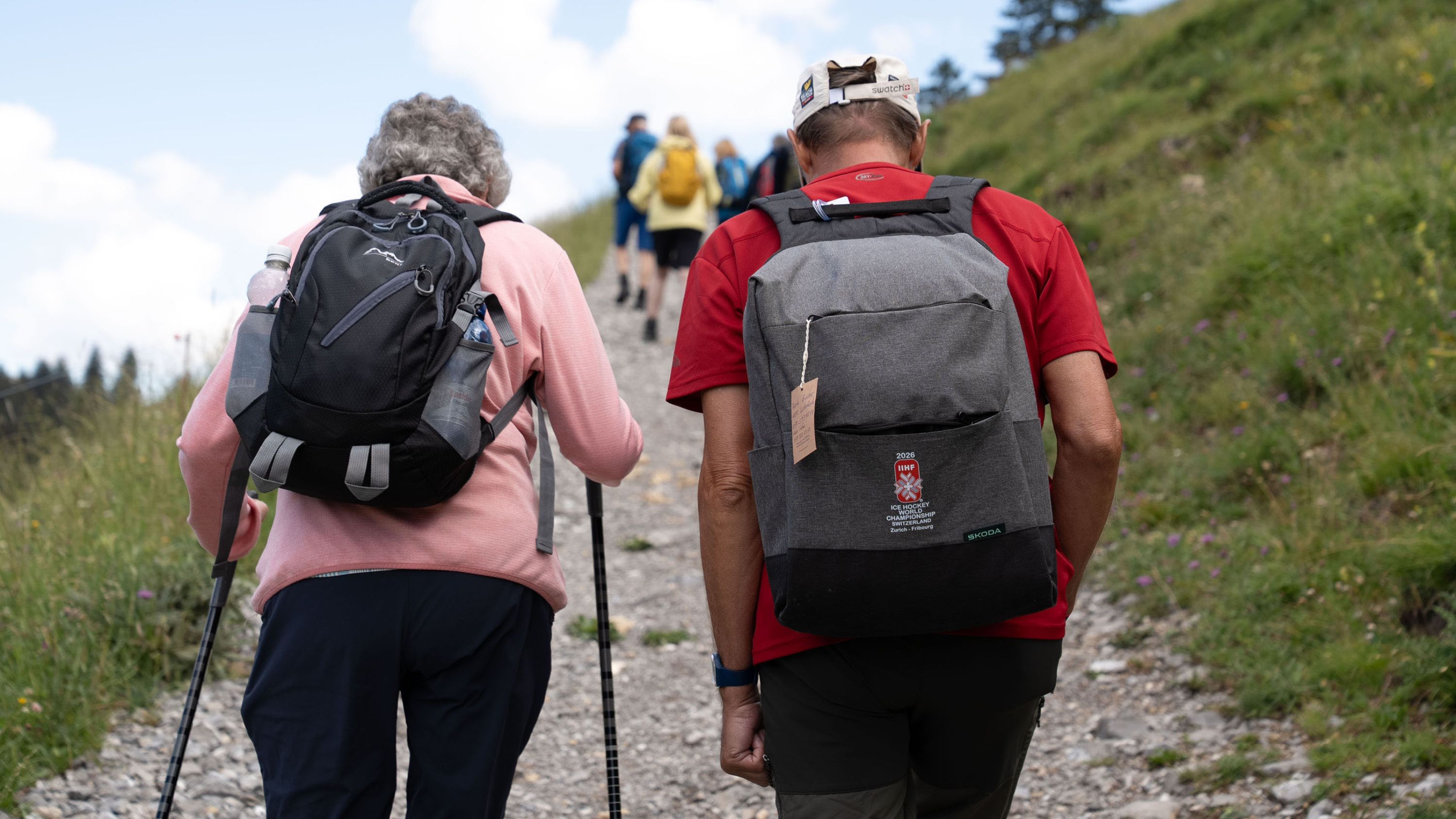 Zwei ältere Menschen laufen gemeinsam auf einem Wanderweg.