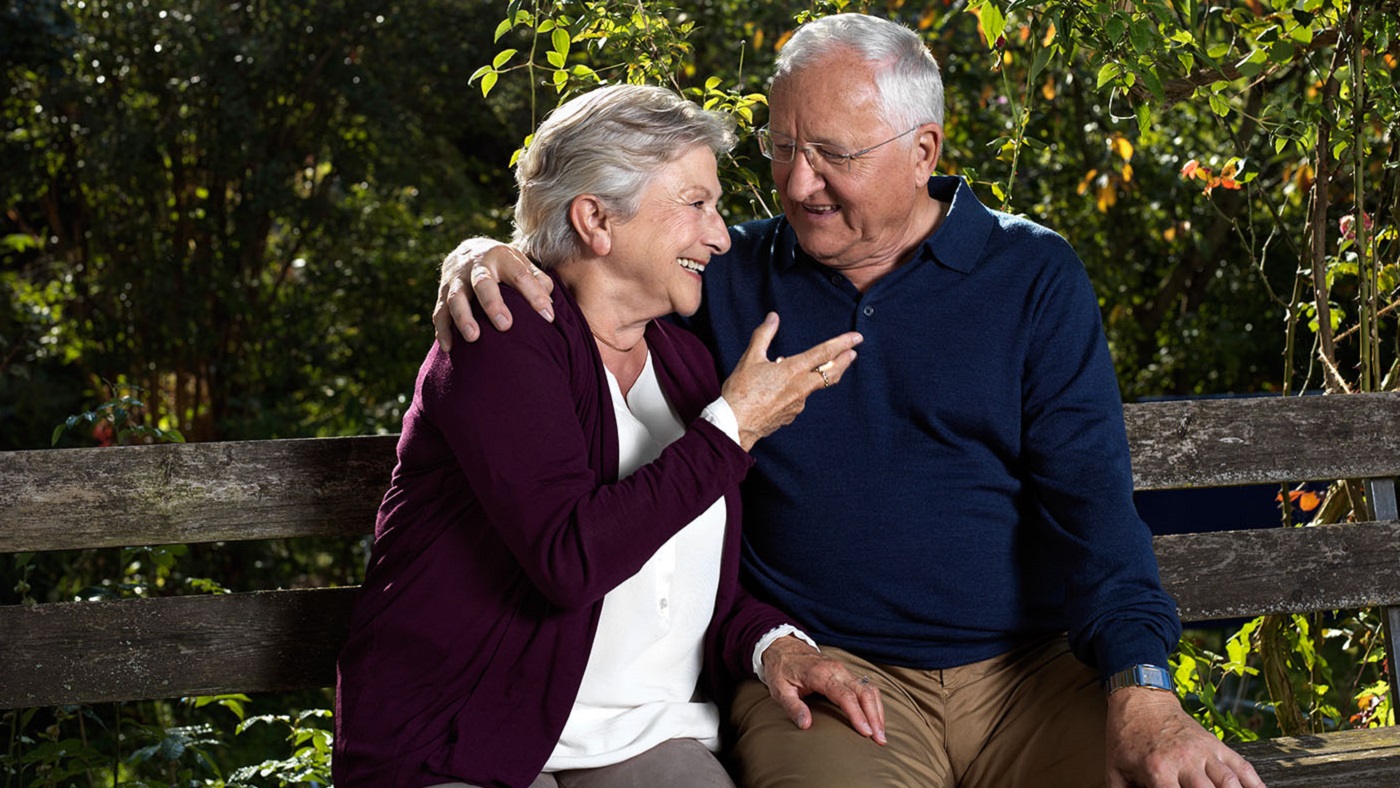 Una coppia di anziani chiacchiera felicemente nel proprio giardino.